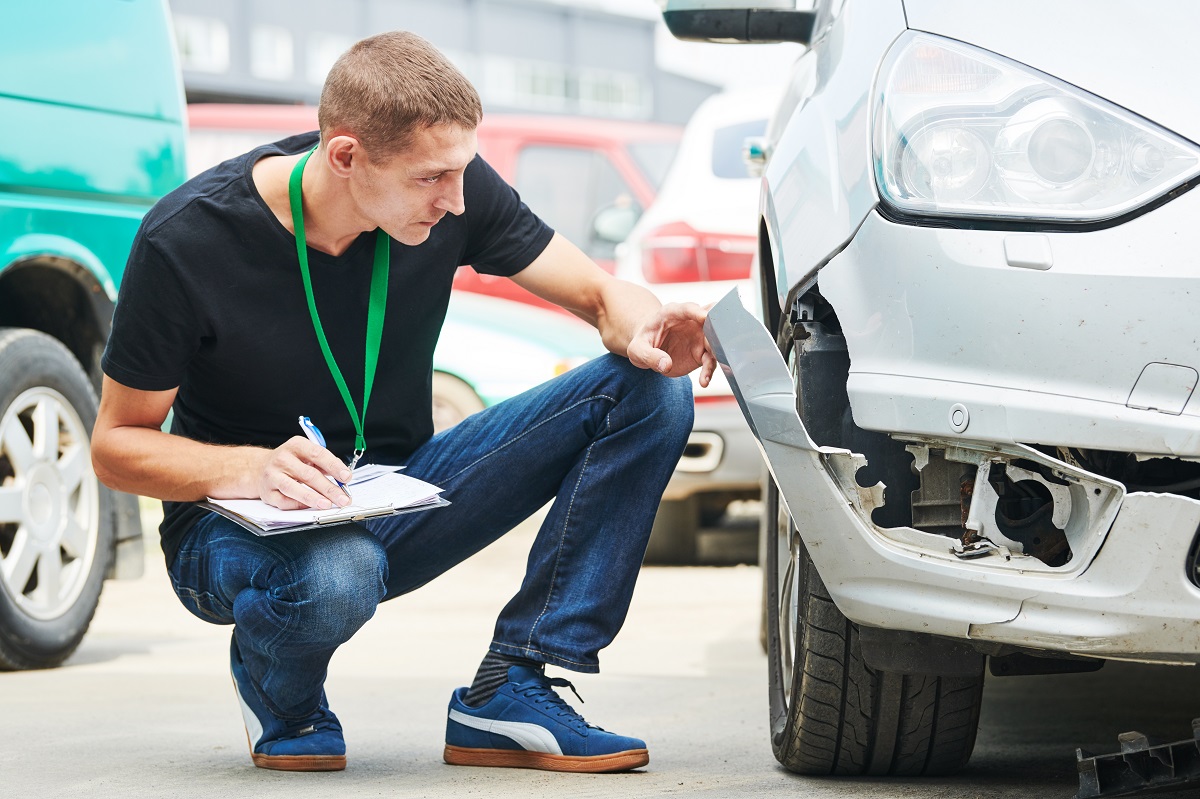 Insurance agent recording car damage on claim form