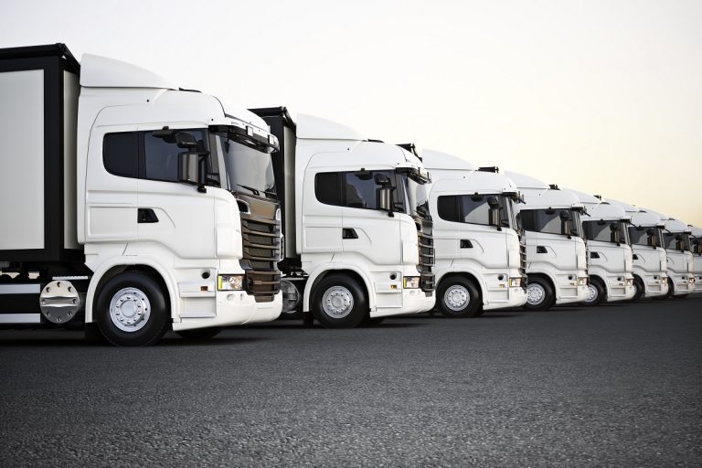 Fleet of white commercial transportation trucks parked in a row ready for business distribution . 3d rendering with room for text or copy space advertisement.